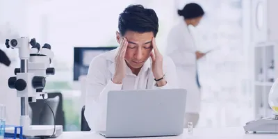 Stressed laboratory worker at a computer illustrating workplace mental health challenges