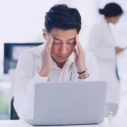 Stressed laboratory worker at a computer illustrating workplace mental health challenges