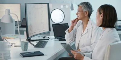 Laboratory personnel discussing AI data on screens