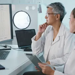 Laboratory personnel discussing AI data on screens