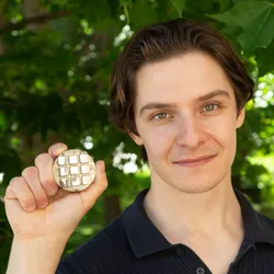 Researcher holds a sample of 3D-printable metal alloy in a garden.