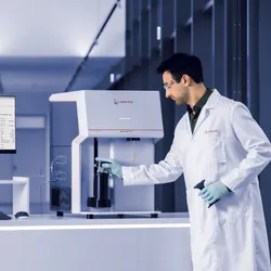 A researcher loads a sample into Anton Paar's Autosorb 3300 chemisorption analyzer, with analysis software shown on a nearby monitor.