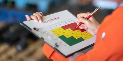 Action of a person is using ballpoint pen to marking on the risk assessment matrix table at "High risk" level.