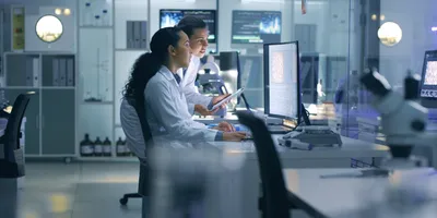Two life scientist researchers viewing scans on computer screen in the lab.