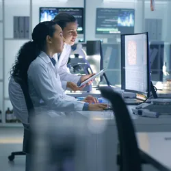 Two life scientist researchers viewing scans on computer screen in the lab.