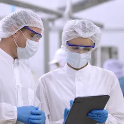 Two workers in food testing facility looking at tablet
