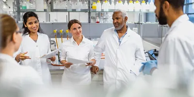 Five scientists standing in the lab, discussing a lab design project