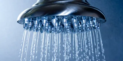 Close-up of a showerhead spraying water, relevant to decontamination practices.