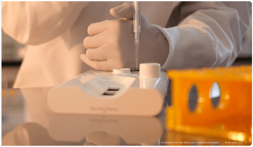 Gloved laboratory staff pipettes a sample into a sequencing cartridge to prepare for a run.