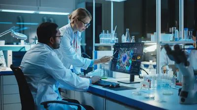Female Research Scientist with Bioengineer Working on a Personal Computer with Screen Showing Virus Analysis Software User Interface.