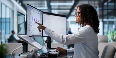 Young African Woman Reviews data on Laptop And Desktop Computers in laboratory