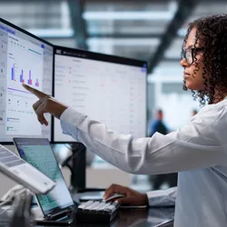 Young African Woman Reviews data on Laptop And Desktop Computers in laboratory