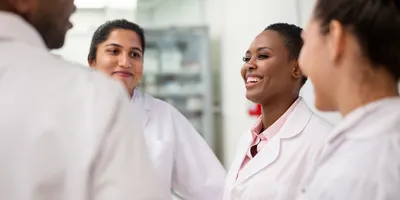 Group of medical researchers discussing and smiling in laboratory, representing diversity