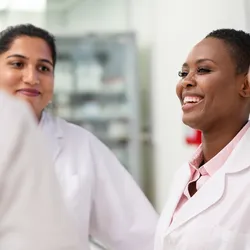 Group of medical researchers discussing and smiling in laboratory, representing diversity