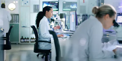 female scientist sitting in chair and viewing results on a screen in pathology lab