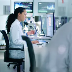 female scientist sitting in chair and viewing results on a screen in pathology lab