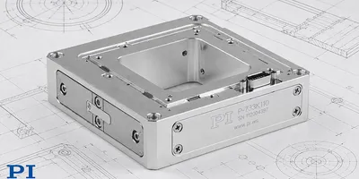 The PI P-733K110 aluminum XYZ piezo nanopositioning stage positioned on engineering blueprint drawings, showing connectors and precision flexure housing.