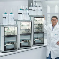 A scientist stands next to three configurations of the Metrohm OMNIS IC automated ion chromatography system in a modern laboratory setting.