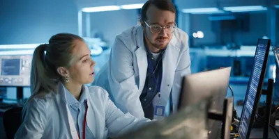 Two lab staff collaborating on a project at a computer