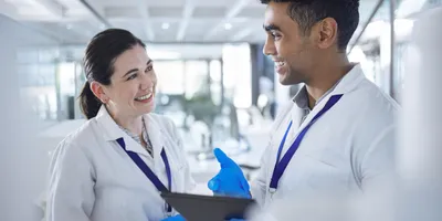 Two lab staff smiling in the lab, representing a strong safety culture.