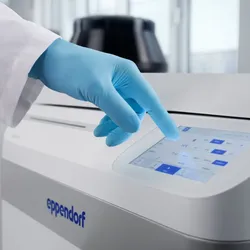 A gloved hand touches the 7-inch display of the Eppendorf SpinPro 8 R high capacity centrifuge, with a dark centrifuge rotor visible in the background.