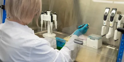 Lab worker pipetting in fume hood
