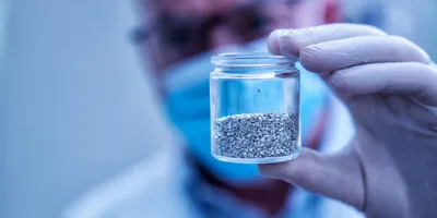 Researcher holding a jar of metal alloy samples for precipitation-induced recrystallization