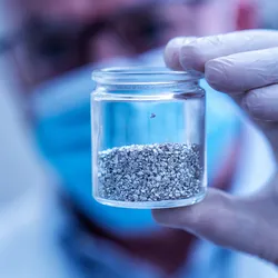 Researcher holding a jar of metal alloy samples for precipitation-induced recrystallization