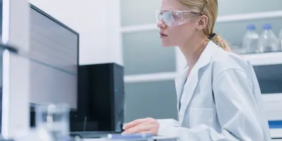 Pharmaceutical laboratory professional using computer for AI tasks