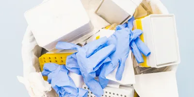 Laboratory waste including containers and gloves in a bin